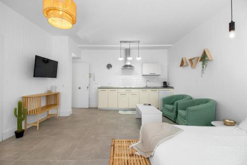 ein weißes Wohnzimmer mit einem Bett und einer Küche in der Unterkunft Apartamentos GAV in Ronda