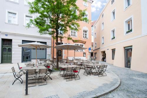 a group of tables and chairs with umbrellas in a courtyard at Pension Goldenes Schiff in Passau