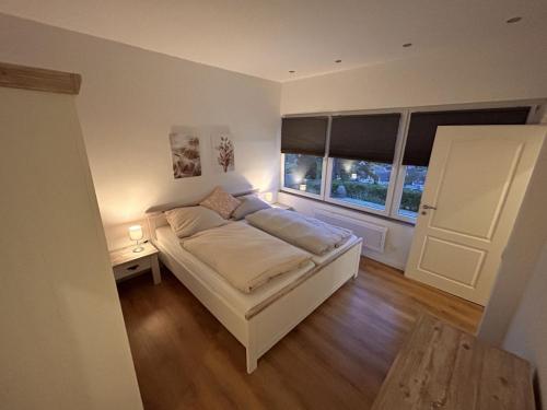 a bedroom with a white bed and a window at Ferienhaus 2-6 Pers Europa Feriendorf neu renoviert mit Sauna in Husen