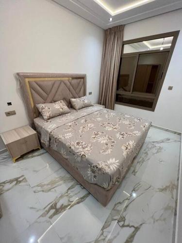 a bedroom with a bed with marble floors and a window at apartment de luxe hay almatar 2 in Nador