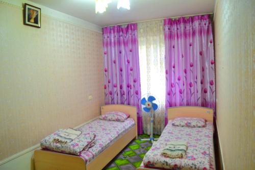 a bedroom with two beds and a window with pink curtains at Osh Guesthouse in Osh
