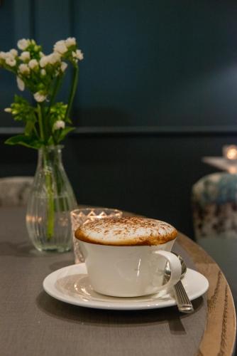 a cup of coffee on a table with a vase of flowers at Clifton Arms Hotel in Lytham St Annes