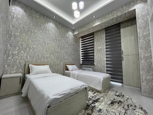 Samarkand luxury apartment #5 في سمرقند: غرفة نوم بسريرين وجدار