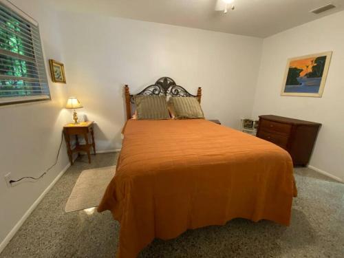 a bedroom with a large bed with an orange blanket at Vintage Vero Bungalo II in Vero Beach