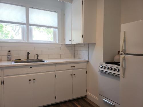 a kitchen with white cabinets and a sink and a refrigerator at Little Fig Hotel in Bar Harbor