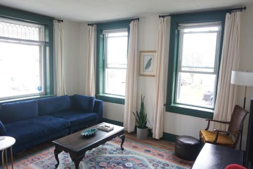 a living room with a blue couch and two windows at Charming Victorian Home In Historic District in Newburgh