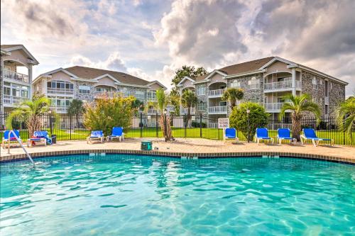 a swimming pool with blue chairs and condos at Golf, Swim and Unwind at Bright Myrtle Beach Condo! in Myrtle Beach