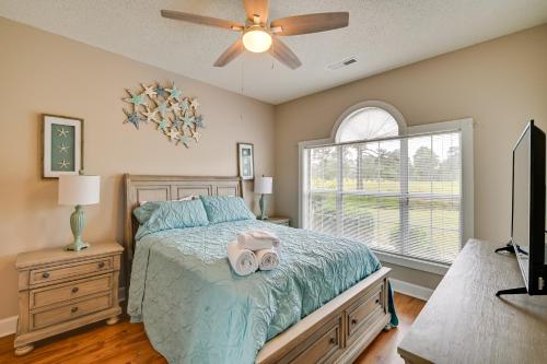 a bedroom with a bed with a ceiling fan and a window at Golf, Swim and Unwind at Bright Myrtle Beach Condo! in Myrtle Beach