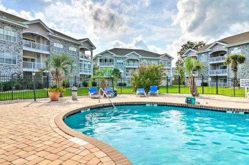 a swimming pool in a courtyard with apartment buildings at Golf, Swim and Unwind at Bright Myrtle Beach Condo! in Myrtle Beach