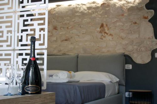a bottle of wine sitting on a table next to a bed at Muricis in Santeramo in Colle