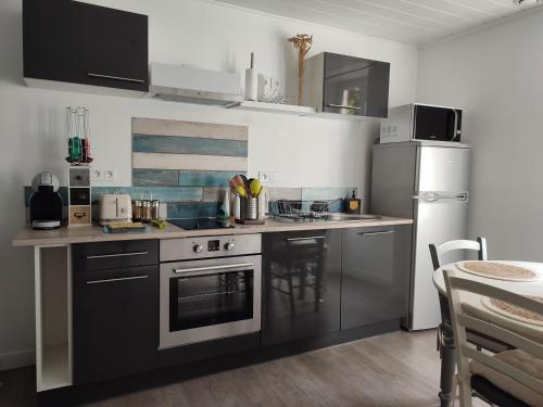 a kitchen with black and white appliances and a table at Les Insolites de Champeix in Champeix