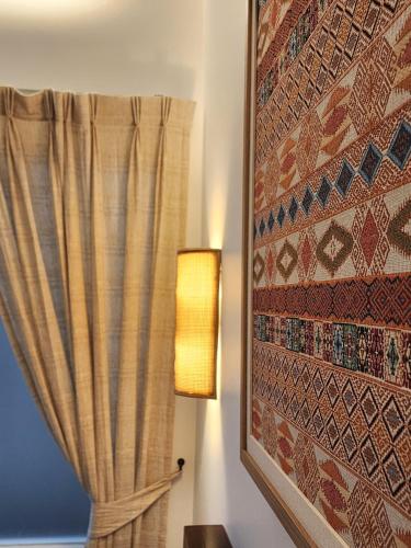 a lamp next to a window with a curtain at The Peaberry Boutique Hotel in Chiang Mai