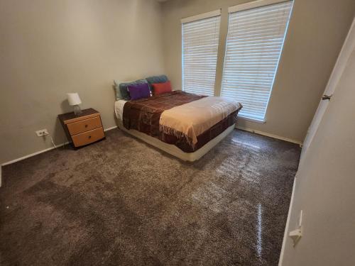 a bedroom with a bed and a nightstand and a window at Five Minutes from At&t Stadium, Globe Life & More in Arlington