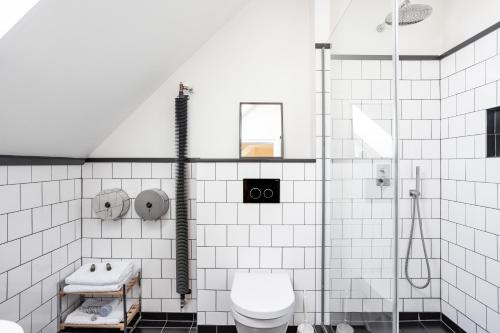 a white tiled bathroom with a toilet and a shower at Sir Toby's Hostel in Prague