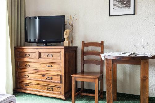 a tv on a dresser with a table and a chair at Willa Apart in Zakopane