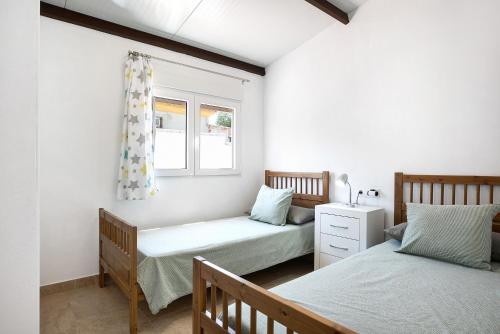 Un dormitorio con dos camas y una ventana. en Casa Naranjos, en El Soto