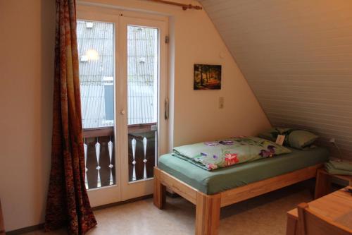 um pequeno quarto com uma cama e uma janela em Bauernhof-Gästezimmer Waldblick em Buchenbach
