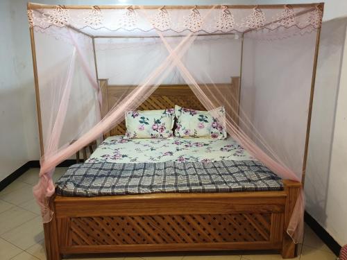 a bed with a canopy with two pillows on it at Zion Care Homestay in Arusha