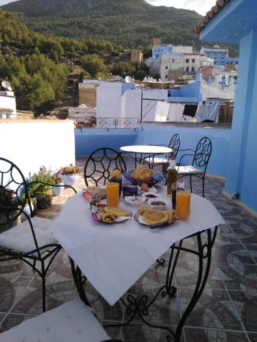 a table with food and drinks on a balcony at Résidence chaounia d'hote in Chefchaouene