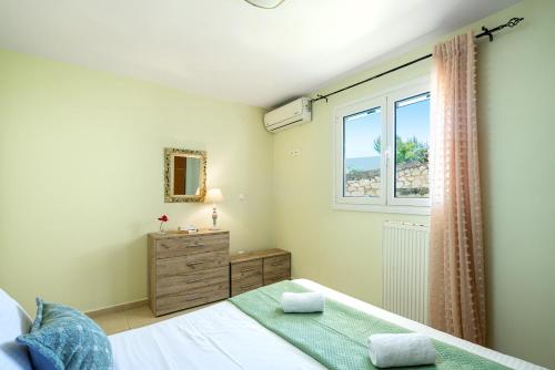 a bedroom with a bed and a window and a dresser at House M.A.S.S. in Sitia
