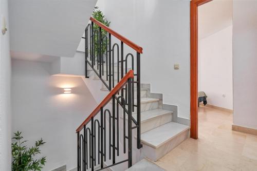 a staircase in a house with white walls and wooden railings at Apartamento Alcazar in Almuñécar