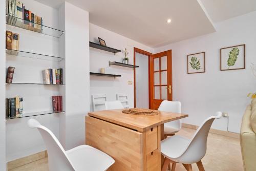 a dining room with a wooden table and white chairs at Apartamento Alcazar in Almuñécar