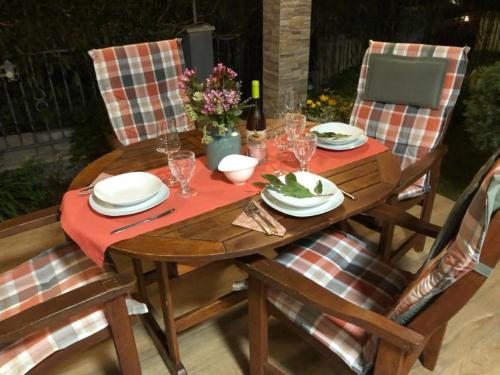 una mesa de madera con sillas, platos y copas de vino en Sunset Apartment with a private yard at Medulin Riviera, en Medulin
