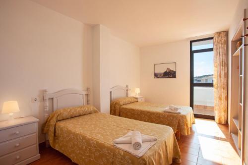 a hotel room with two beds and a window at Apartamentos Don Quijote in Cala Ratjada