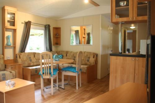 een keuken en eetkamer met een tafel en stoelen bij Chalet with large veranda 6p centrally located in National Park, Swimming pool in Wateren