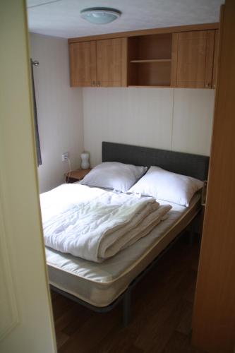 a bedroom with a bed with white sheets on it at Chalet with large veranda 6p centrally located in National Park, Swimming pool 168 in Wateren