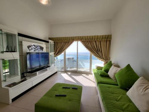 a living room with a green couch and a television at Beachfront Holiday Homes in Ajman 
