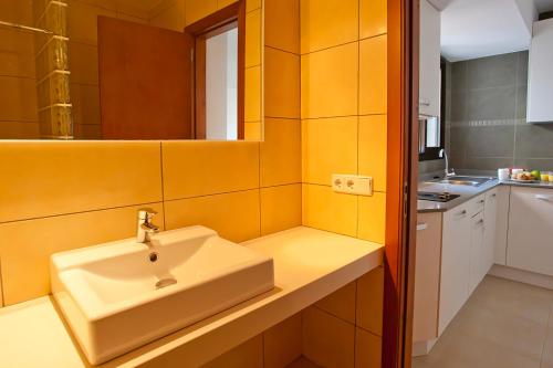 a bathroom with a white sink and a kitchen at Apartamentos Don Quijote in Cala Ratjada