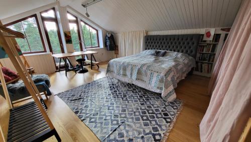 um quarto com uma cama, uma mesa e janelas em Wonderful wooden house next to lake and Stockholm archipelago em Boo