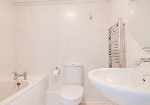 a white bathroom with a toilet and a sink at Loveday in Porthleven