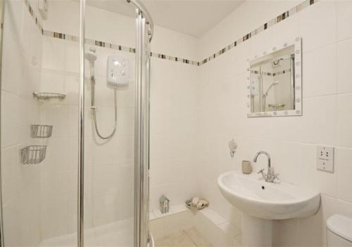 a white bathroom with a shower and a sink at Blue Horizon in St Ives