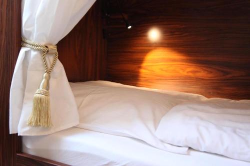 a bed with white sheets and a wooden head board at Old Kings Design Hostel in Füssen