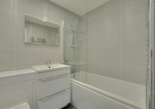 uma casa de banho branca com um lavatório e um chuveiro em Pool and Valley View em Mawgan Porth