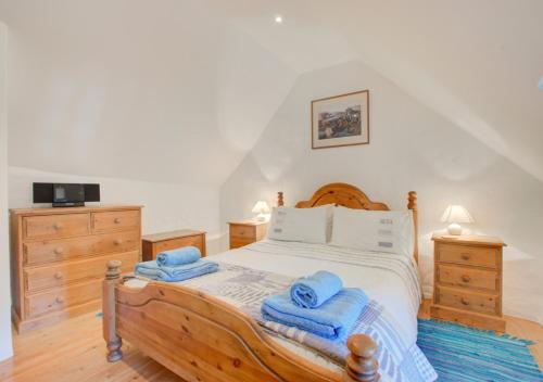a bedroom with a wooden bed with towels on it at Renes Cottage in Ruan Minor