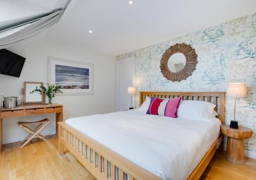 a bedroom with a bed and a desk with a mirror at St Cadoc in Padstow