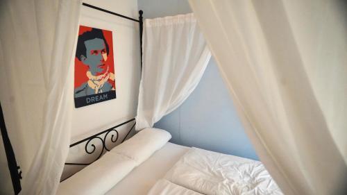 a bedroom with a bed with white curtains and a painting at Old Kings Design Hostel in Füssen