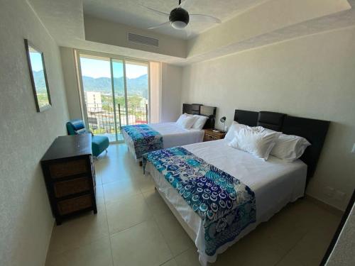 a hotel room with two beds and a window at Ocean front Grand Venetian corner condo in Puerto Vallarta