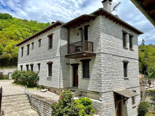 un antiguo edificio de ladrillo con balcón. en Giagia Evgenia, en Vitsa