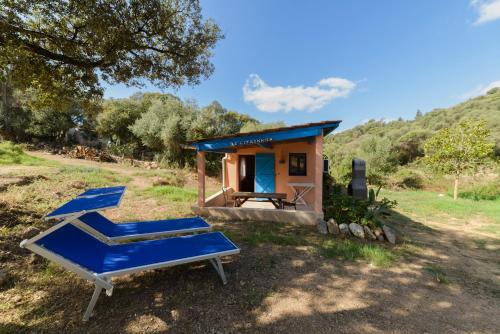 a tiny house with blue lounge chairs in front of it at Résidence Itylon in Cargèse