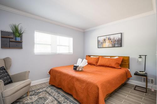 a bedroom with a bed with orange sheets and a chair at NEW Spacious Decatur Oasis w Fire Pit, Mins to ATL in Decatur