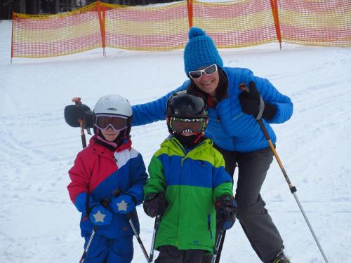 a woman and two children on skis in the snow at Apartement Gute Laune in Mieming