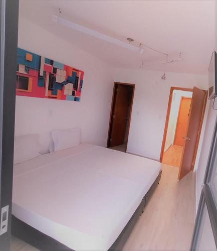 a bedroom with a white bed and a painting on the wall at Hotel BLH 2 in Bucaramanga