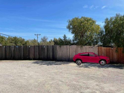 a red car parked next to a wooden fence at 30 PCT OFF! Malibu Charming Suite, Ocean View, King Bed in Malibu