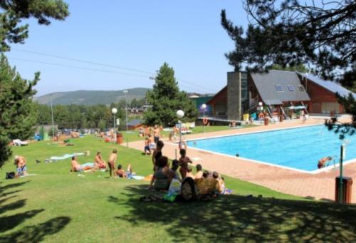 a group of people sitting in the grass near a swimming pool at La Molina - acogedor apartamento cerca de las pistas de esquí in La Molina