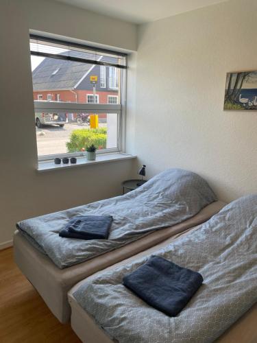 two beds in a room with a window at Havne huset in Nakskov