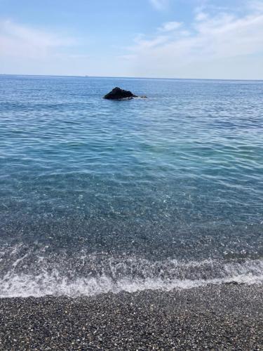 a rock in the water next to a beach at Casa ORRI by Farris & Cors in Genova